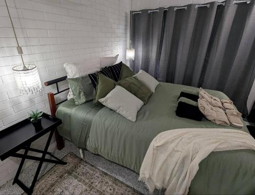 ein Schlafzimmer mit einem großen grünen Bett mit Kissen in der Unterkunft Peaceful, Modern, LowToxic, Bfast included in Brisbane