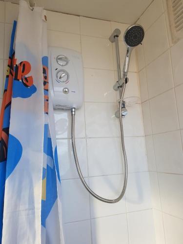 a shower with a shower head in a bathroom at Guest house in rear garden in Eltham