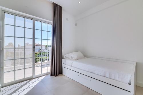 a bedroom with a bed and a large window at Casa Nuria com 4 quartos, piscina e churrasco em Vale do Lobo in Almancil