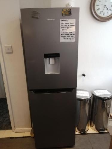 a black refrigerator with a trash can in a room at Guest house in rear garden in Eltham