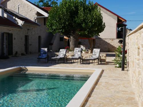 a swimming pool in a yard with chairs and a tree at Villa Didova kuca ZadarVillas in Podlug