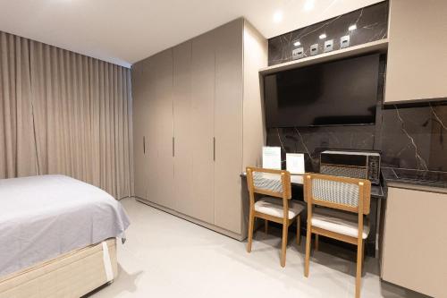 a bedroom with a bed and a desk with two chairs at Estúdios modernos no Empiria by WeHousy in Luis Eduardo Magalhaes
