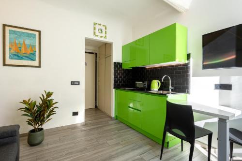 een keuken met groene kasten en een tafel bij La Casetta Verde con Vista Mare - Nel cuore del Parasio e delle Logge di Santa Chiara in Imperia
