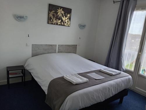 a bedroom with a bed with two towels on it at Hôtel Le Lyon Vert Commentry in Commentry