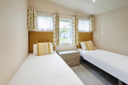 Dos camas en una habitación con dos ventanas. en Woodpecker Lodge with Hot Tub, en York