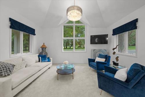 ein Wohnzimmer mit einem weißen Sofa und blauen Stühlen in der Unterkunft 2BR Guesthouse Near Lakes with BBQ & Hot Tub in Blue Springs