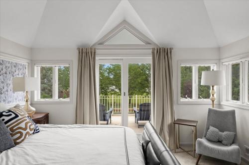 ein Schlafzimmer mit einem Bett und einem Stuhl und Fenstern in der Unterkunft 2BR Guesthouse Near Lakes with BBQ & Hot Tub in Blue Springs