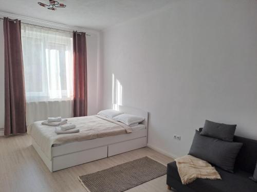 a white bedroom with a bed and a chair at Studio One in Făgăraş