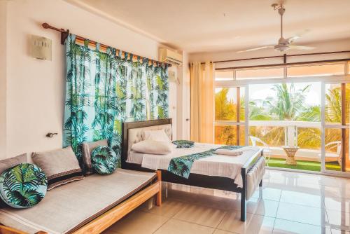 une chambre avec un lit, un canapé et une fenêtre dans l'établissement Beachfront-Homes 1st Avenue Nyali, à Mombasa