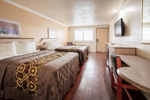 una camera d'albergo con due letti e una scrivania di Budget Inn Corcoran Near Tulare CA 43 a Corcoran