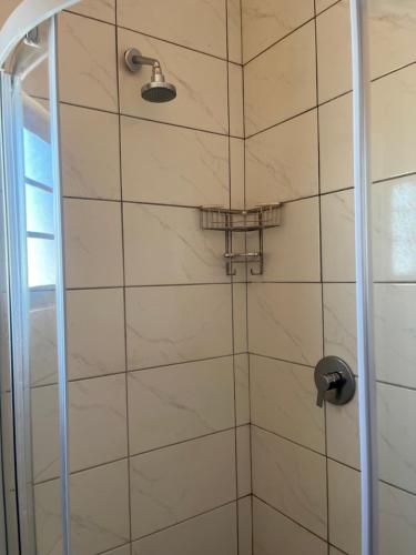 a shower with a glass door and a shower head at 101 Maia in Gqeberha