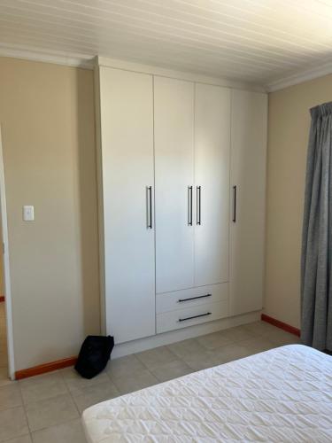 a bedroom with white cabinets and a bed at 101 Maia in Gqeberha