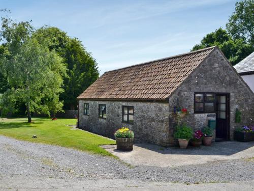 a small stone building with flowers in front of it at Ramscliff Cottage in Cheddar