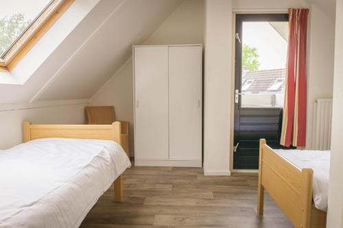 Un dormitorio abuhardillado con dos camas y una ventana. en Vakantiepark Sallandshoeve, en Nieuw-Heeten