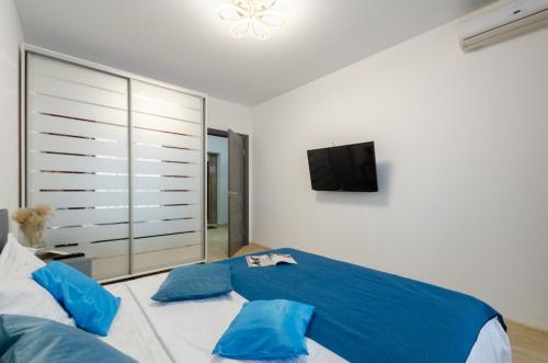 a bedroom with a bed with blue pillows and a tv at Your Flat Lebedinny in Kyiv