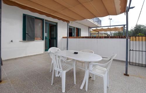 a white table and chairs on a patio with an umbrella at 2 Bedroom Amazing Apartment In Casal Velino in Castellammare di Velia