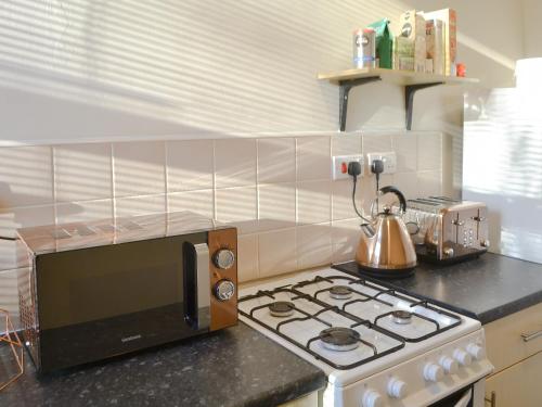 a kitchen with a stove and a microwave on a counter at Marley's Retreat in Seaton Delaval