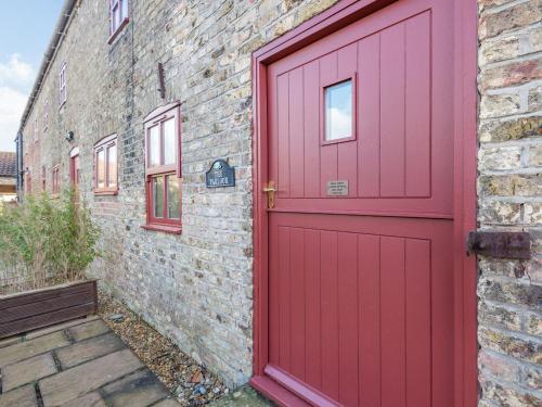 a red door on the side of a brick building at The Parlour - Uk37517 in Routh
