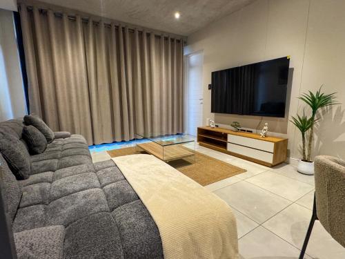 ヨハネスブルグにあるSecure and modern private flat Houghton Estateのソファと薄型テレビのあるリビングルーム