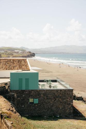 a building with a beach in the background at Moinho da Areia - Boutique Hotel in Azores in Ribeira Grande