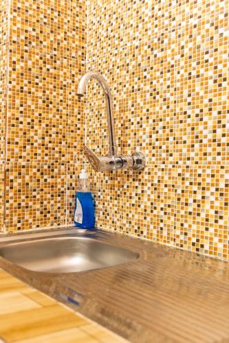 a kitchen sink with a faucet in a tiled wall at Casa Hôtel Résidence in Abidjan