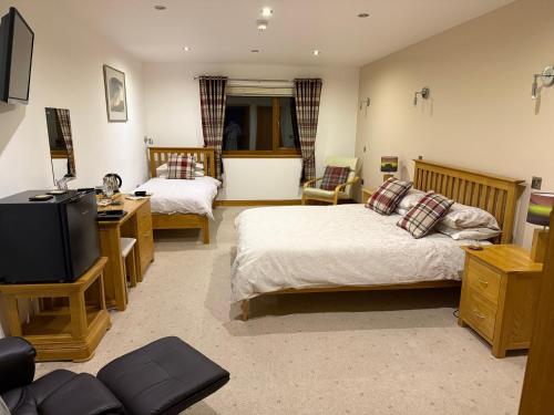 オークニー諸島にあるAvalon Guesthouseのベッド2台とテレビがあるホテルの部屋