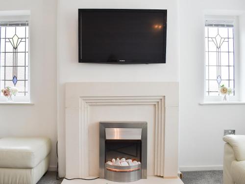a living room with a fireplace with a flat screen tv above it at Berwick Lodge in Thornton