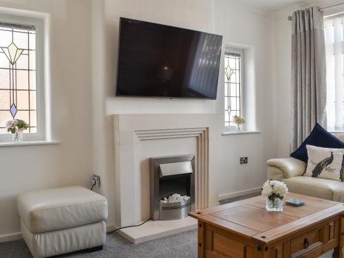 a living room with a fireplace with a flat screen tv at Berwick Lodge in Thornton