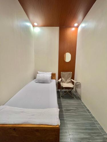 Un pequeño dormitorio con una cama y una silla. en Transient Room Near SM Lipa and LIMA PARK, en Inosloban