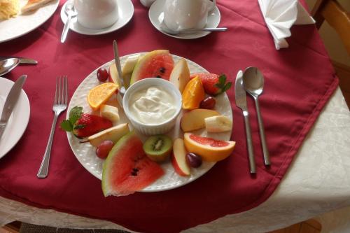 a plate of fruit on a table with forks and spoons at Rockmount House B&B in Clifden