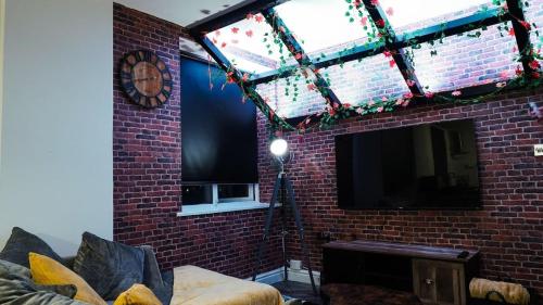 a living room with a brick wall and a television at Spring Close Street in Hunslet