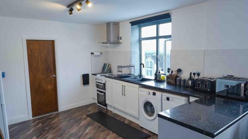 a white kitchen with a washer and dryer in it at Spring Close Street in Hunslet