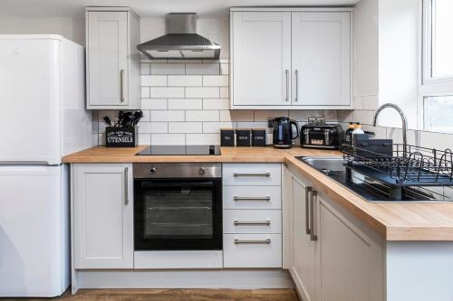 a kitchen with white cabinets and a stove top oven at Cosy One Bed Apt in Leeds City in Leeds