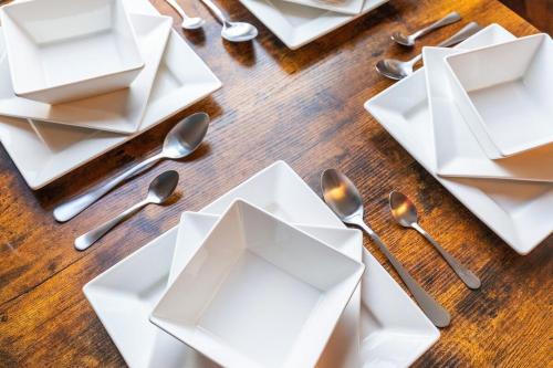a wooden table with white plates and silver spoons at Broomfield Terrace in Headingley