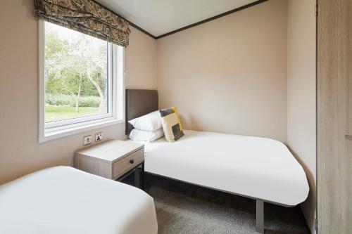 zwei Betten in einem kleinen Zimmer mit Fenster in der Unterkunft Teejay's Lodge with Hot Tub in York