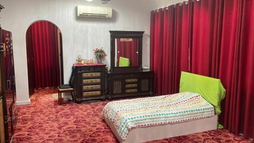 a bedroom with a bed and a dresser and red curtains at Kourosh in Muscat