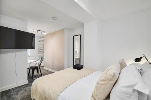 a white bedroom with a bed and a table at Luxury Lower-Level Two Bed Apt in Headingley