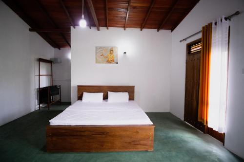 een slaapkamer met een bed met witte lakens en een houten hoofdeinde bij Circle Edge Cabana in Kandy