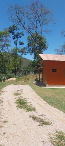 a dirt road in front of a red building at Chalé da Montanha in São Roque