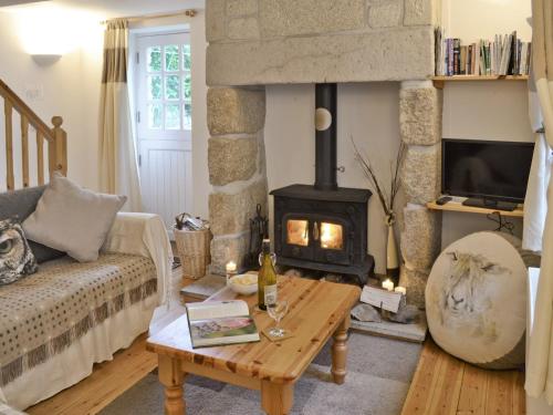 a living room with a fireplace and a couch at Meadow Cottage in St Just