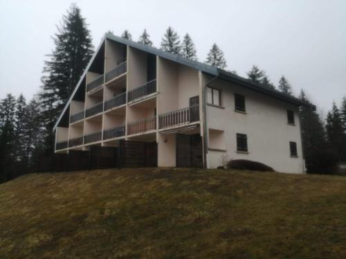 a large white building on a hill with trees at L'Échappée Belle du Lac in Malbuisson