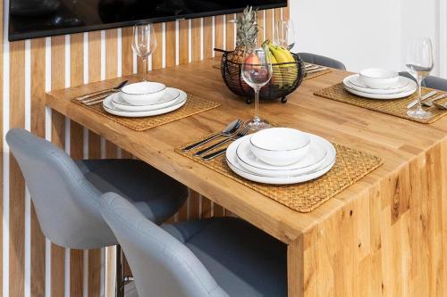 a wooden table with chairs and plates and wine glasses at Popular Two Bed Apt in Leeds City in Headingley