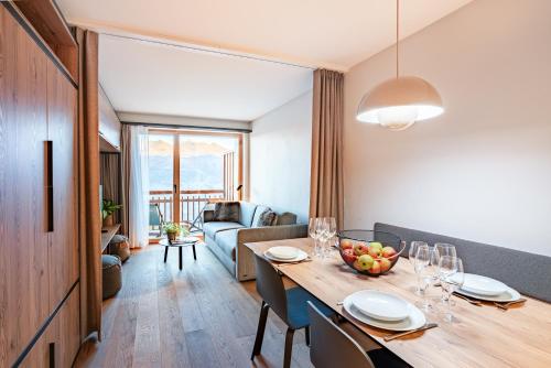 a dining room with a table and a living room at SWISSPEAK Resorts by Pierre & Vacances Premium Thyon in Hérémence