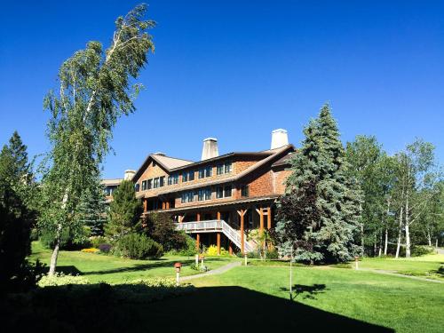 a large building on a grassy field with trees at Sun Mountain Lodge in Winthrop