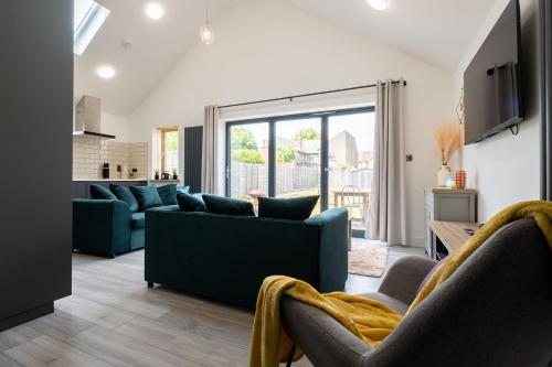 a living room with blue furniture and a large window at 4 bedroom bungalow in Kettering - Garden - Parking - WiFi in Kettering
