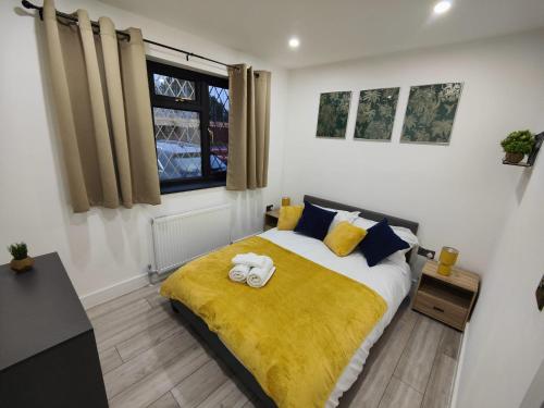 ein Schlafzimmer mit einem Bett mit einer gelben Decke in der Unterkunft 4 bedroom bungalow in Kettering - Garden - Parking - WiFi in Kettering