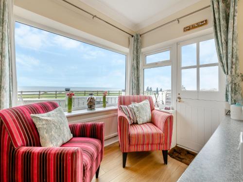 a living room with two chairs and a large window at Toll Bar Cottage in Whitby
