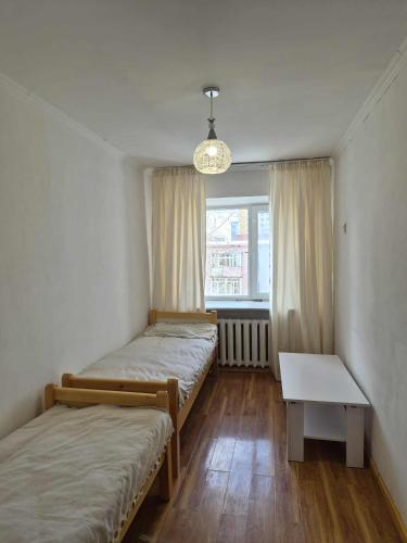 una stanza con due letti, una finestra e un tavolo di Tsese a Ulaanbaatar