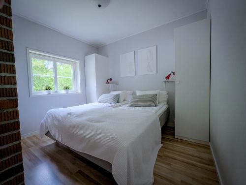 Una habitación blanca con una cama y una ventana en Boats stay play lake cabin, en Broby