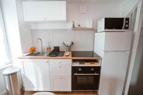 a small kitchen with a white refrigerator and a sink at Charmant T2 plein centre in Saint-Astier